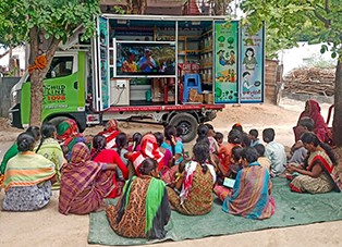 groupe de femmes assise devant un camion d'information